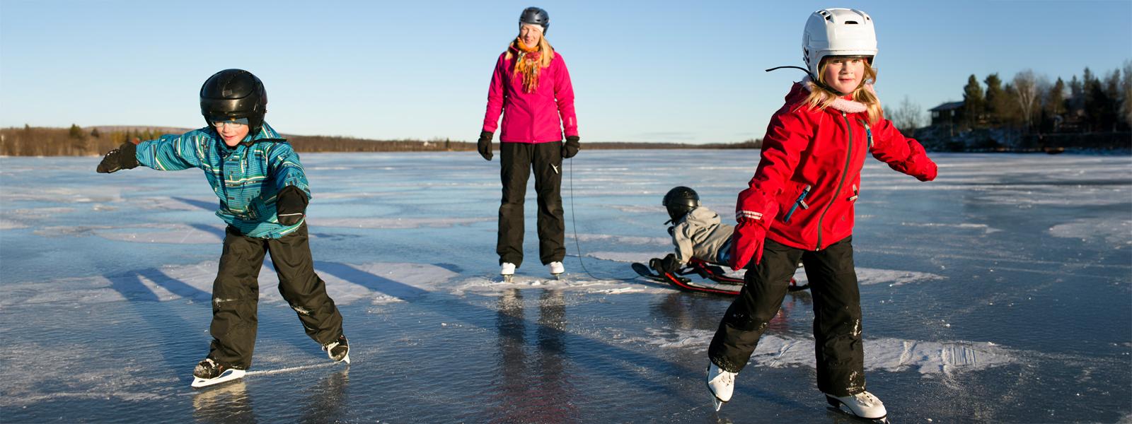 Mother with three kids skating on a small frozen lake.