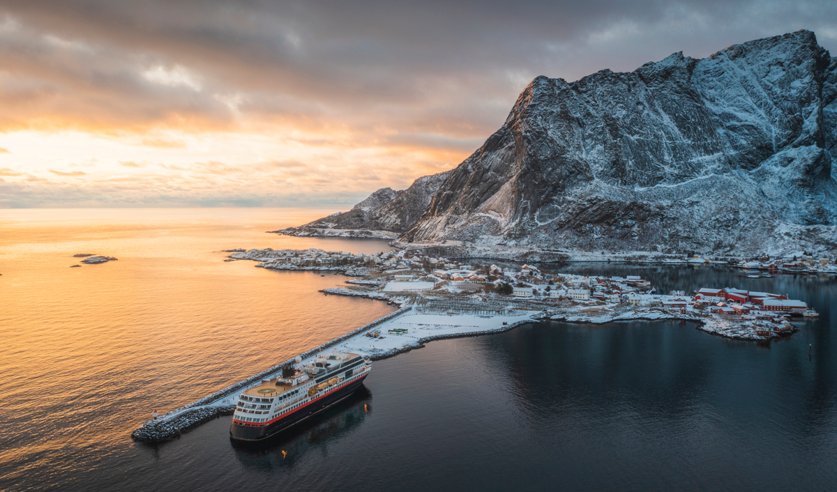 Cruise ship next to a large ice-covered mountain.