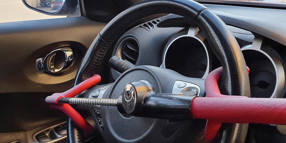 Steering wheel of a car secured with a red anti-theft device.