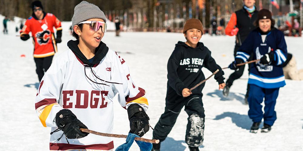 Children playing ice hockey on an outdoor rink.