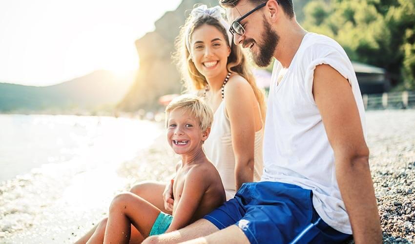 A family sits on the beach and smiles.