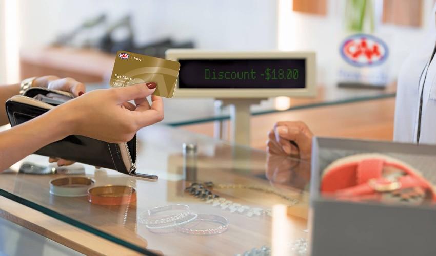 A woman is handing a credit card to a woman at a jewelry store.
