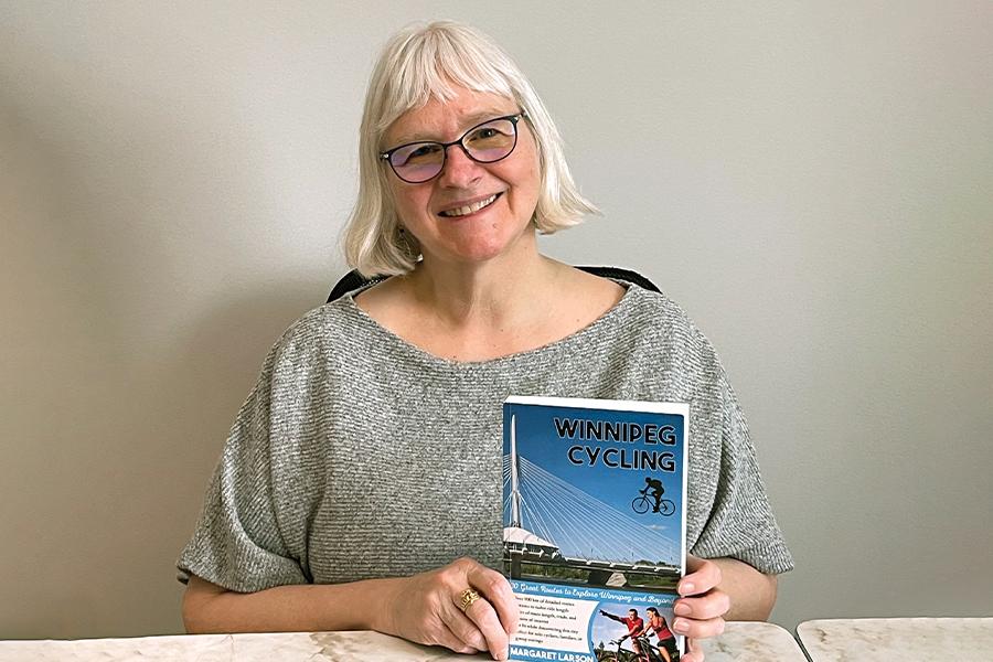A woman sitting at a table holding a book.