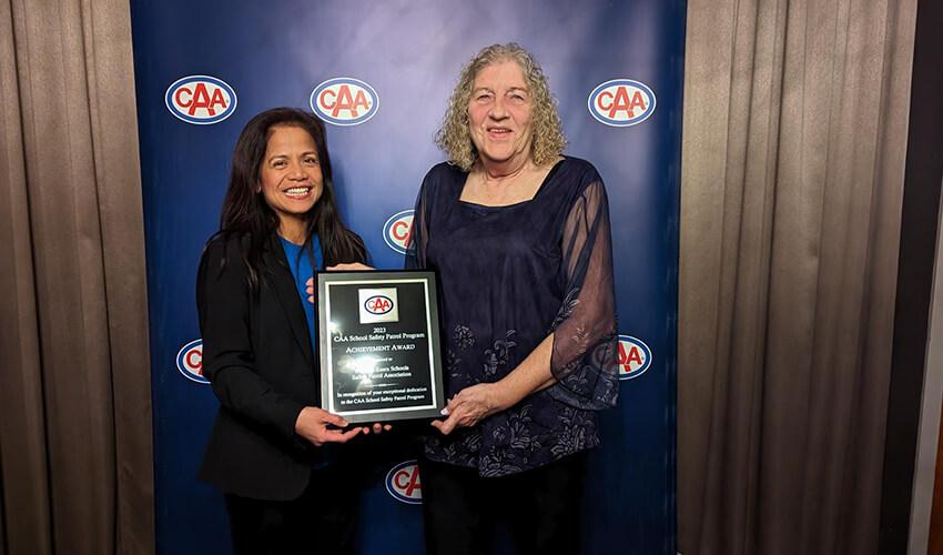 Two women smiling and holding an achievement award at a caa event.