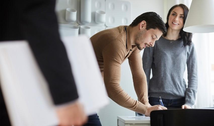 A man and woman are looking at a laptop in an office.
