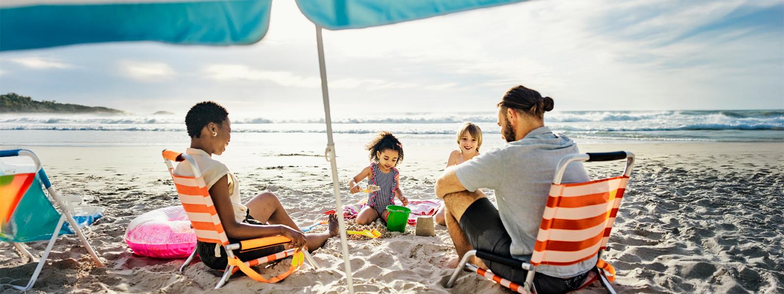 Kids are playing in a sand and parents sitting on a beach.