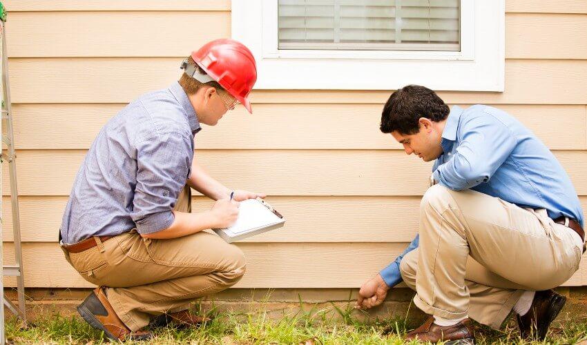 Two men inspecting a house with a clipboard.