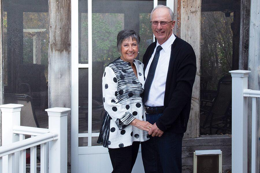 A man and woman standing in front of a porch.