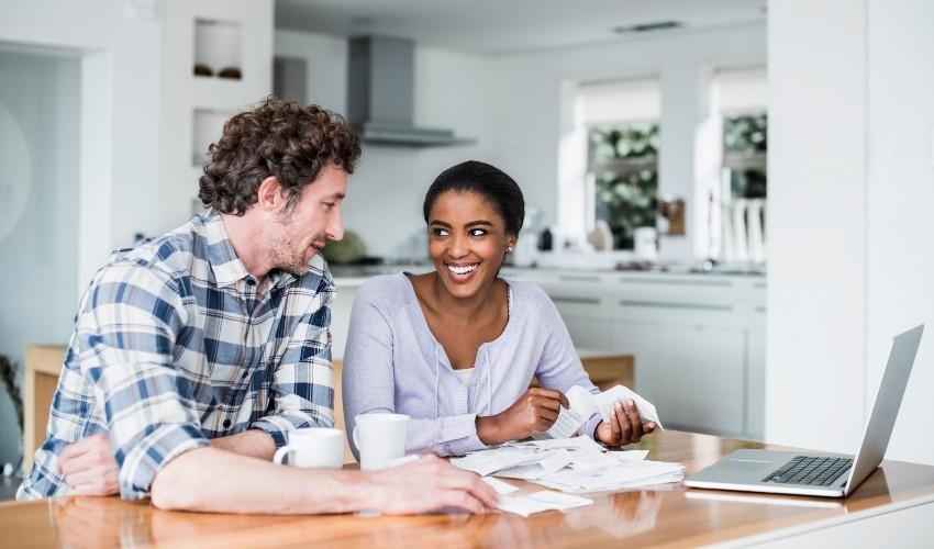 A man and woman are sitting at the kitchen table and looking at their bills.