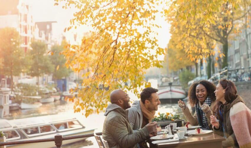 A group of people sitting at an outdoor table near a canal.