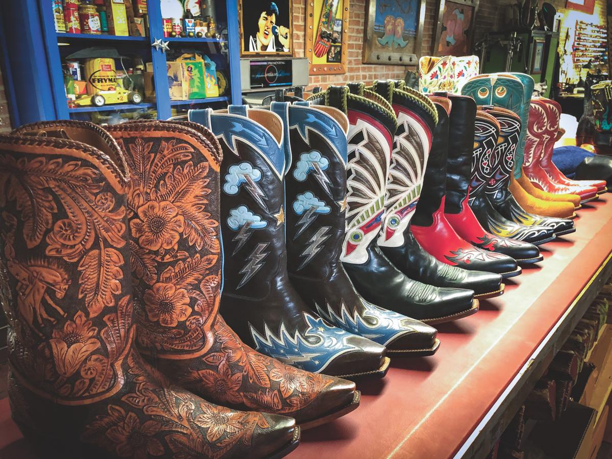 A brown shelf lined with leather cowboy boots in an array of intricate designs and colours.