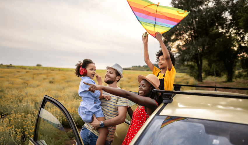 A family with a kite in the back seat of a car.