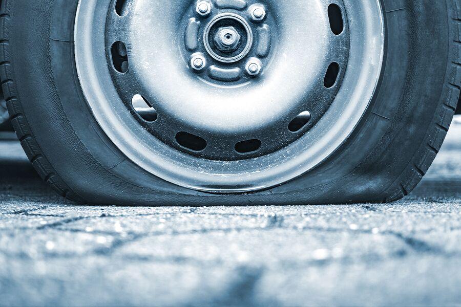 Close-up of a deflated car tire on a vehicle.