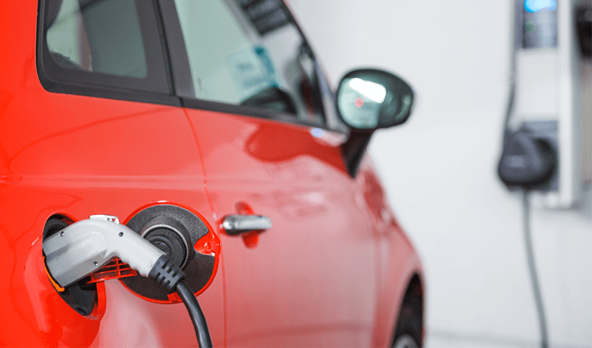 A red car is plugged into an electric charger.
