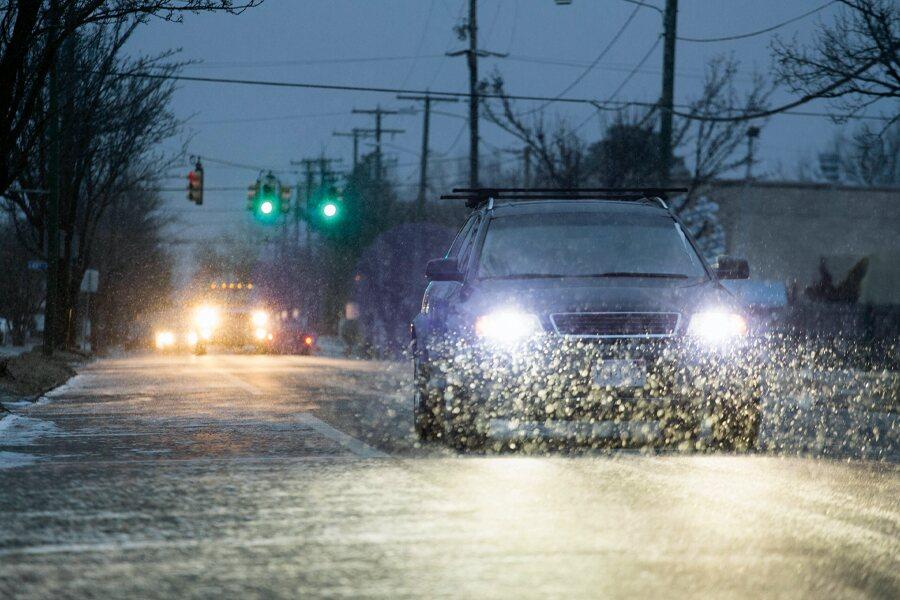 Car driving on a wet road during a heavy rain with headlights on.