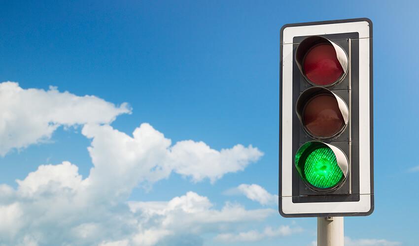 A traffic light with a green light and a blue sky.