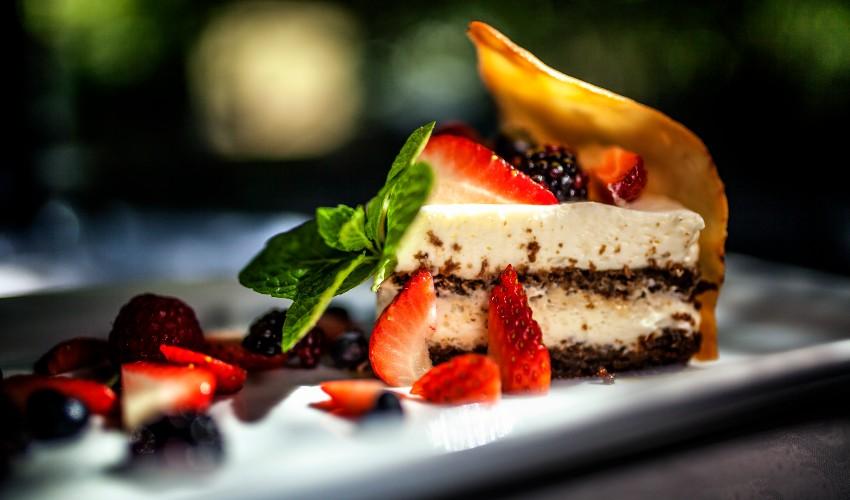 A piece of cake with berries and mint on a plate.