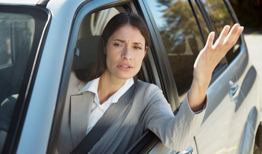 A woman waving her hand out of the window of a car.