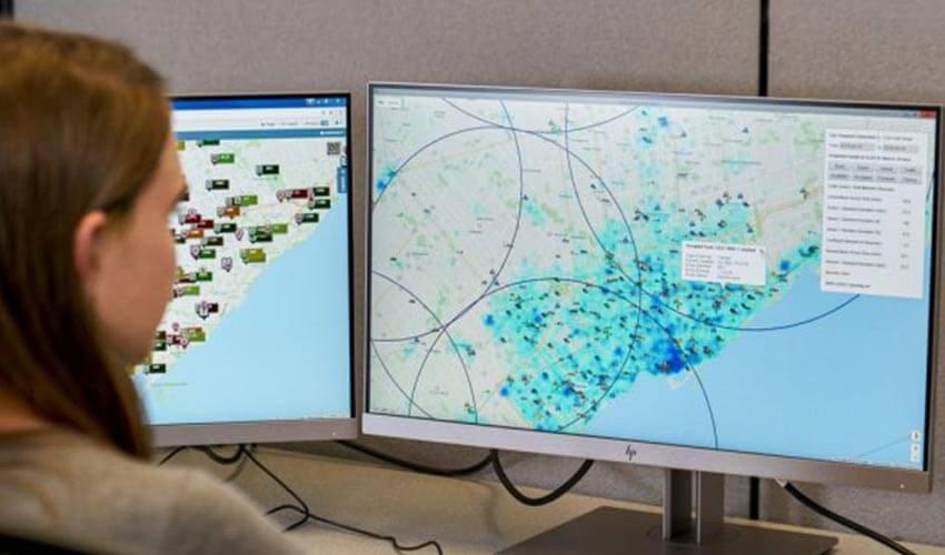 A woman is looking at a map on two monitors.
