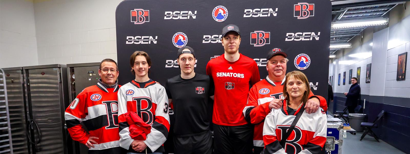 A group of people wearing red and white hockey jerseys pose for a picture.