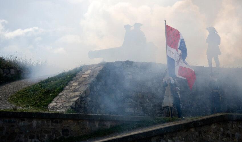 A group of people standing on top of a wall with smoke coming out of it.