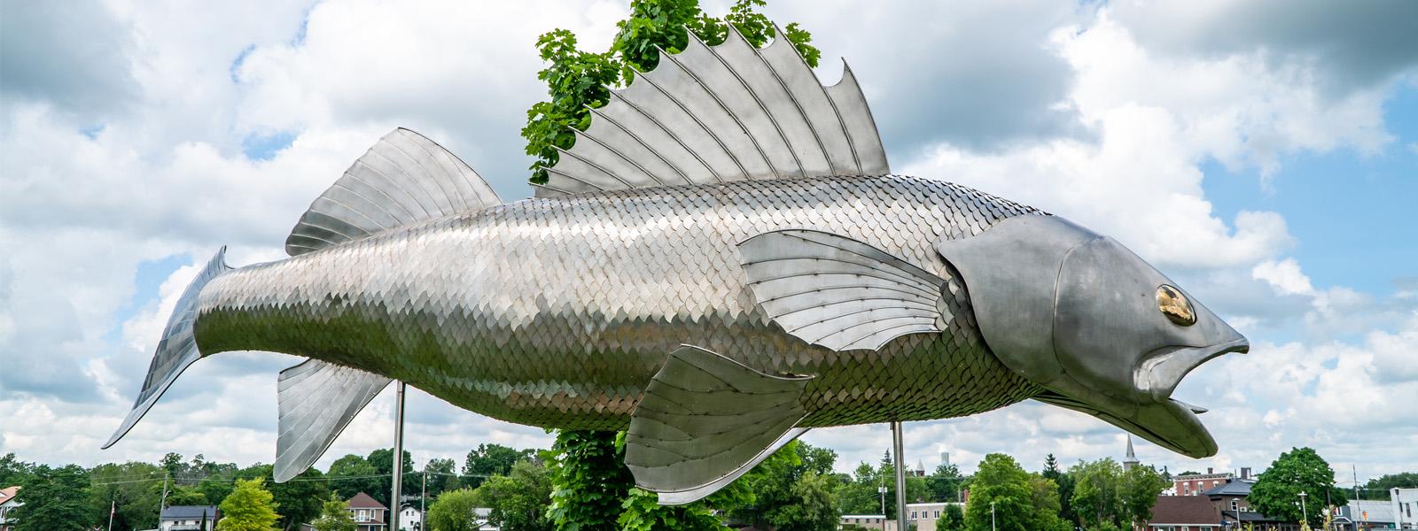 A stainless-steel fish sculpture with large fins and an open mouth.