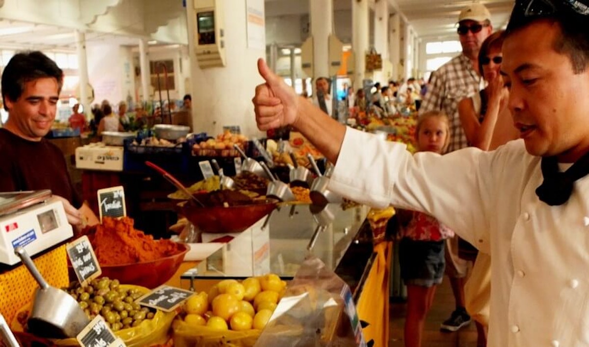 A chef is pointing to a man at a food stand.