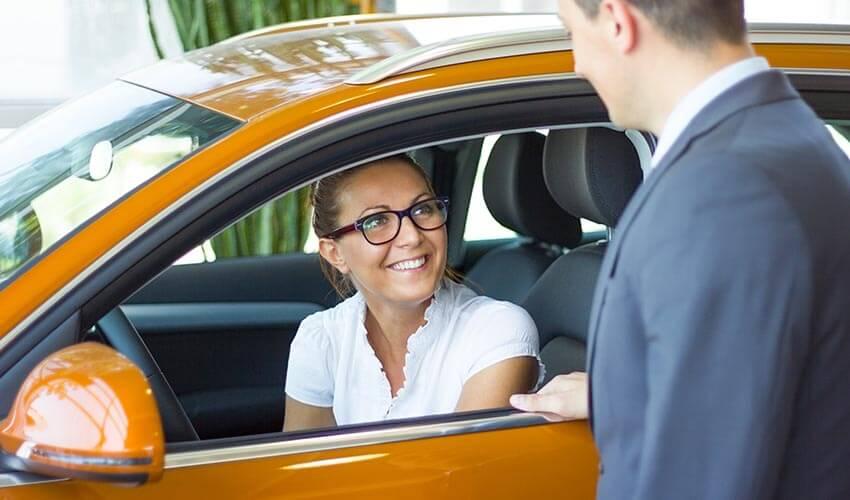 A man and woman looking at a car in a showroom.