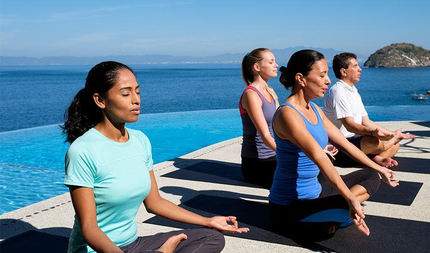 A group of people doing yoga on the deck of a cruise ship.