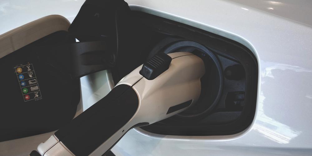 A close up of a white electric car charging.