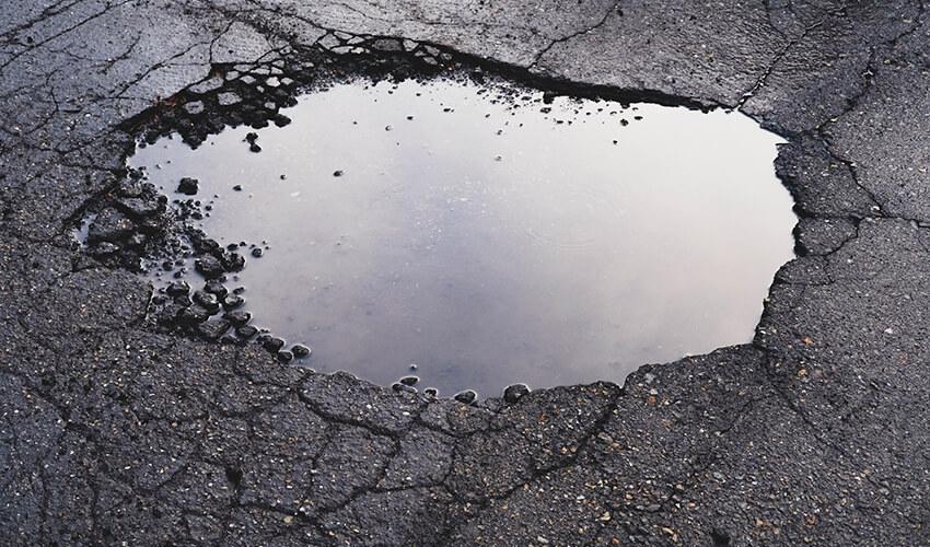 A puddle of water in a pothole on an asphalt road.