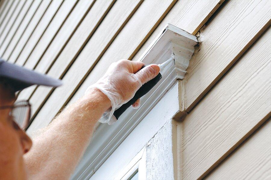 A man is using a tool to clean the siding of a house.