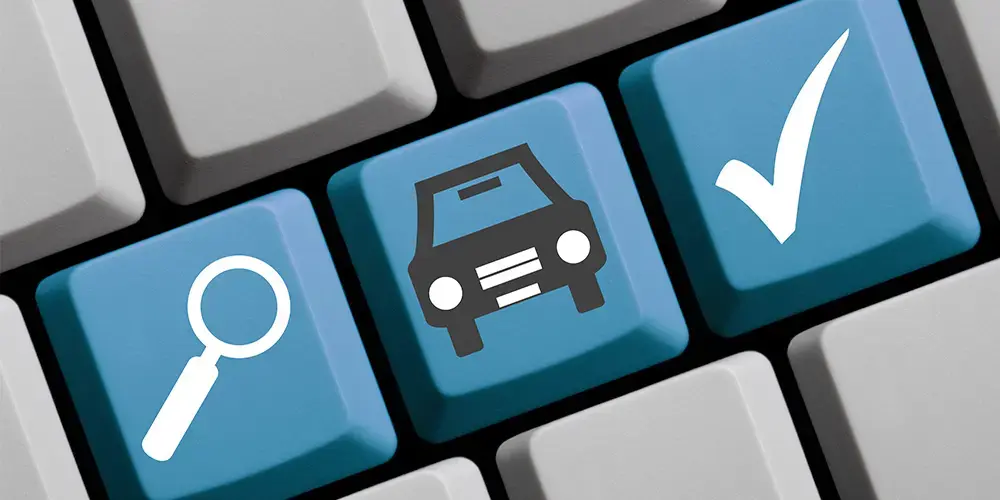 A close-up of a keyboard, where three keys are highlighted in blue: one with a magnifying glass, one with a car and one with a checkmark.