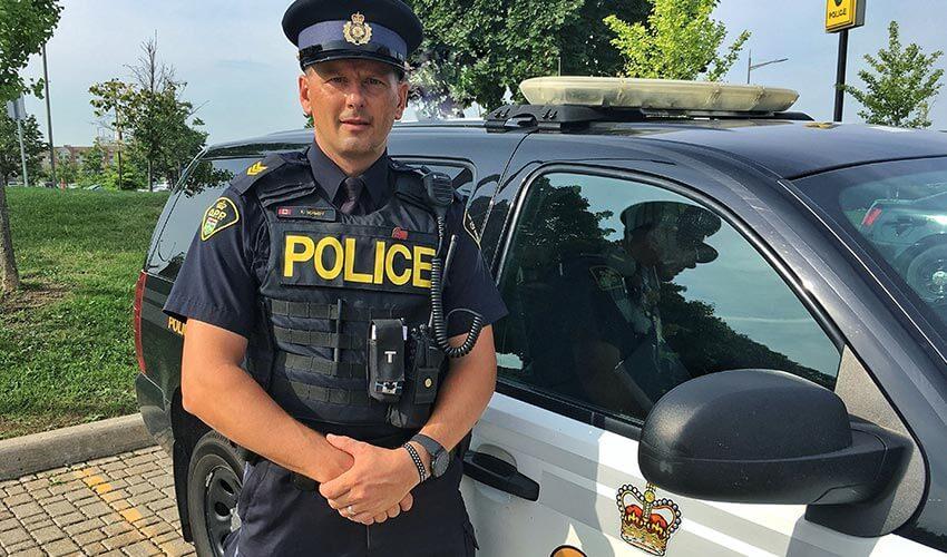 A police officer standing in front of a police car.