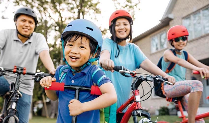 A family on bicycles with a young boy smiling.