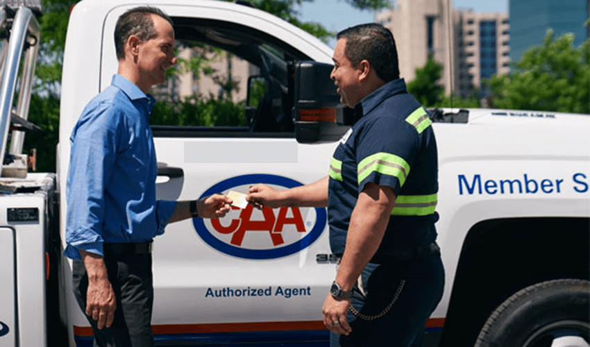 Two men shaking hands in front of a truck.