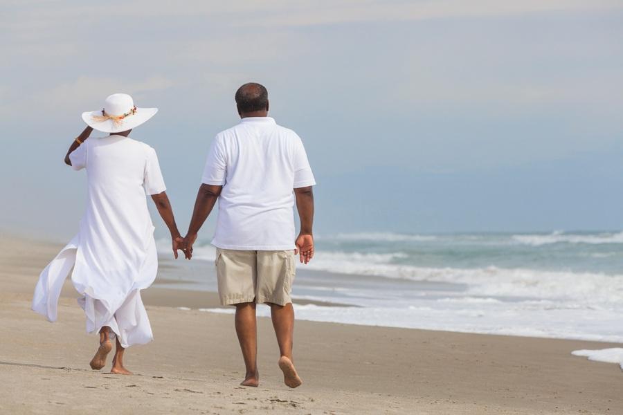 A couple walking on the beach holding hands.