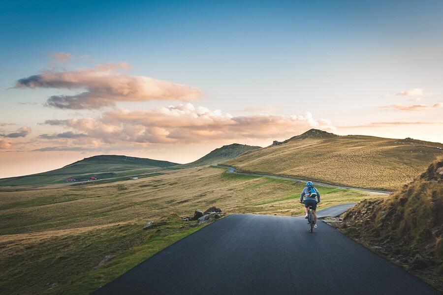 A man riding a bike down a road in the mountains.