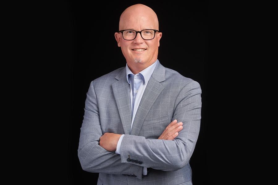 A bald man with glasses and a suit posing for a photo.