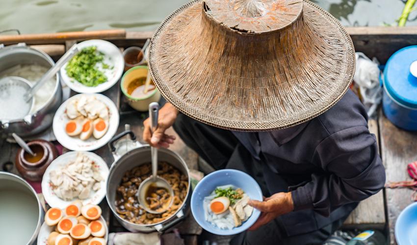 A man in a hat is preparing food on a boat.