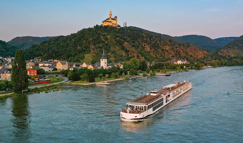 A cruise ship traveling down a river near a town.