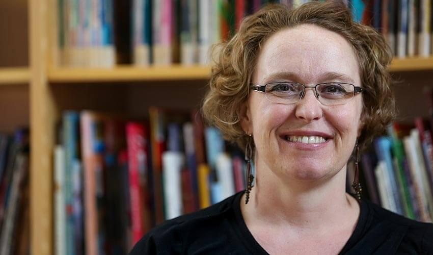 A woman smiling in front of a book shelf.