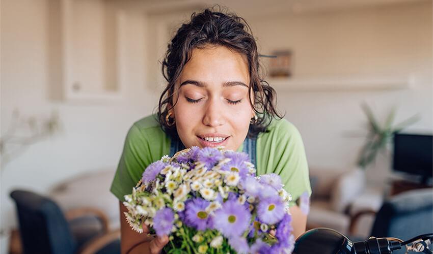 A woman smelling a bouquet of flowers in her living room.