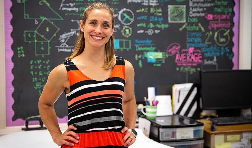 A woman standing in front of a chalkboard.