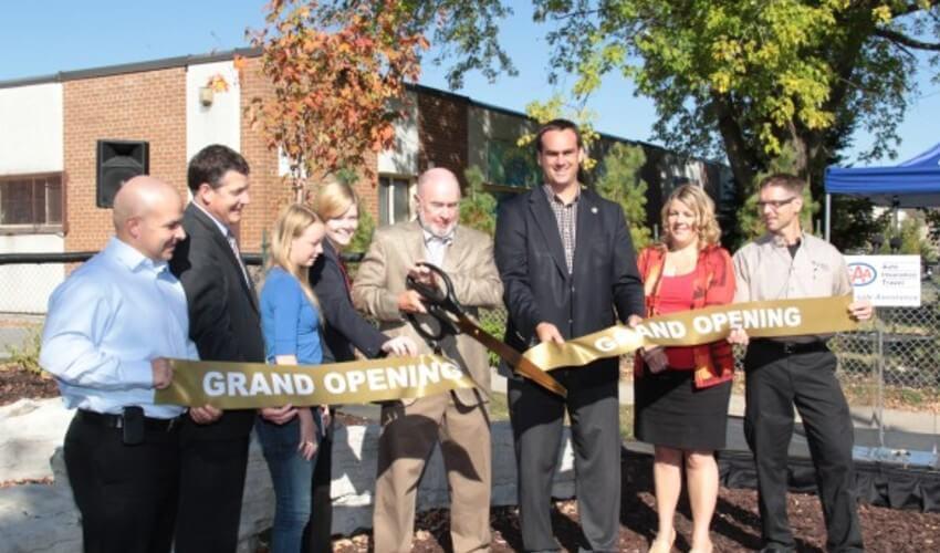 A group of people cutting a ribbon in front of a building.