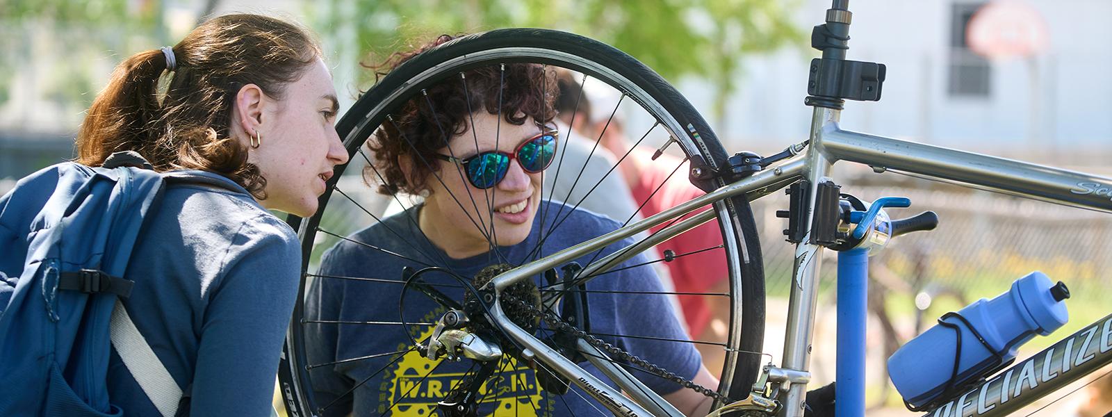 A person helping to repair a cyclist’s bike.