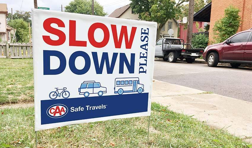 A sign that says slow down in front of a house.