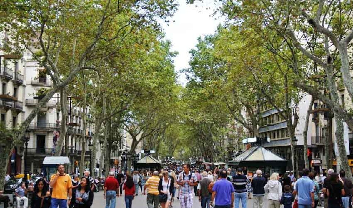 A crowded street in barcelona with lots of trees.
