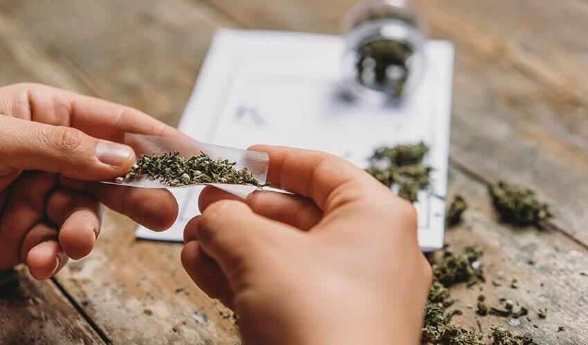 A person is holding a piece of marijuana on top of a piece of paper.