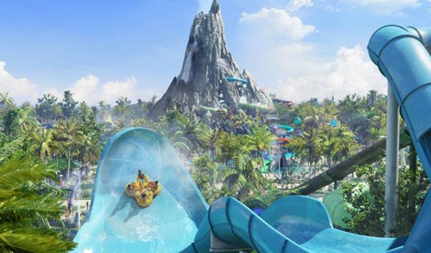 A water slide at a theme park with a mountain in the background.
